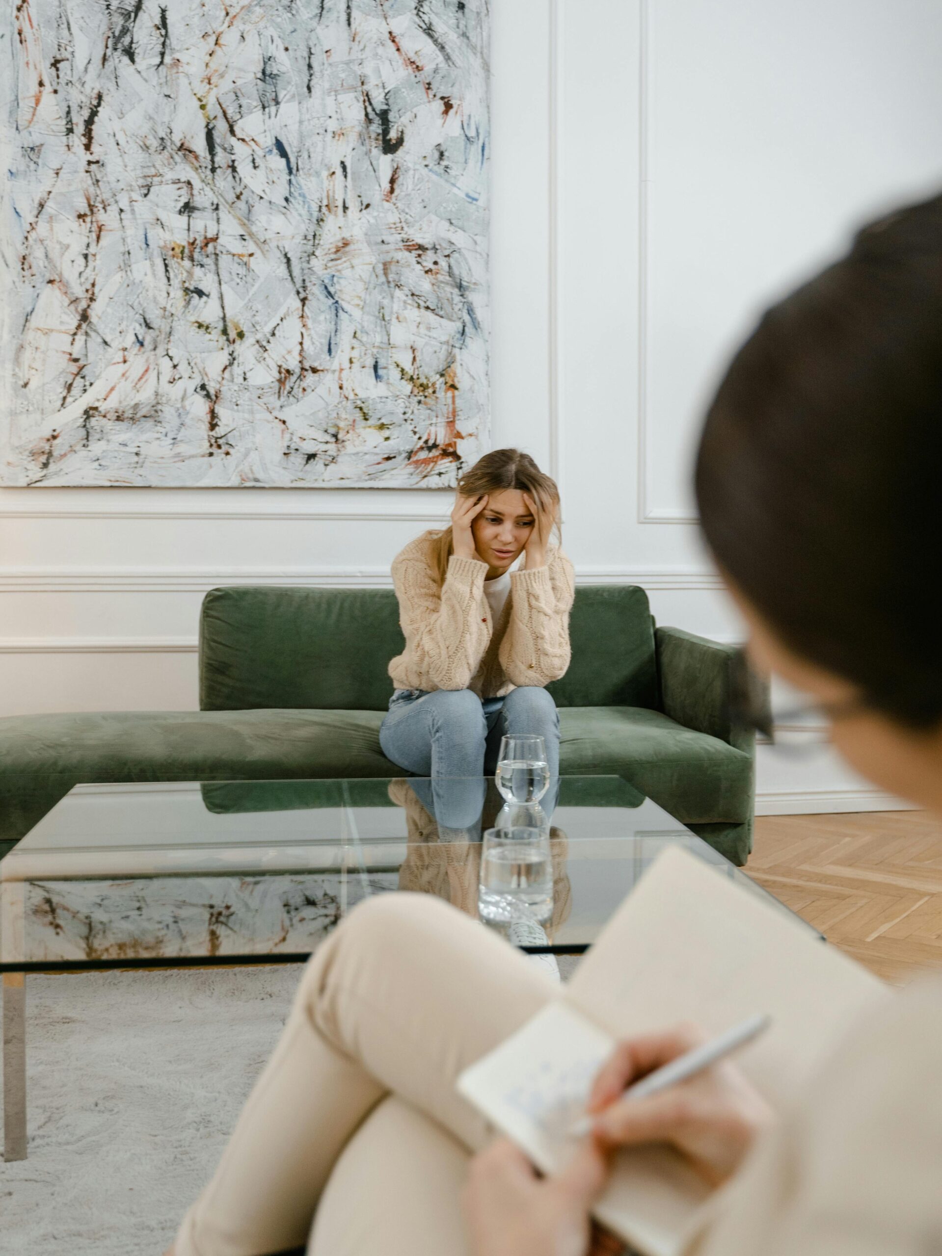 A woman looks distressed during a therapy session indoors, emphasizing mental health support.